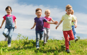 54443941 - summer, childhood, leisure and people concept - group of happy kids playing tag game and running on green field outdoors